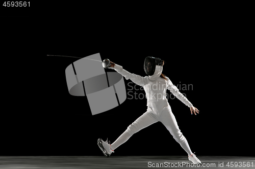 Image of Teen girl in fencing costume with sword in hand isolated on black background