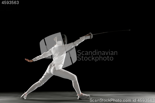 Image of Teen girl in fencing costume with sword in hand isolated on black background