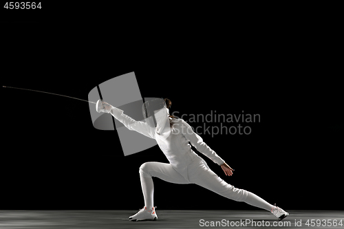 Image of Teen girl in fencing costume with sword in hand isolated on black background