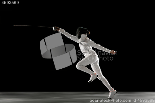 Image of Teen girl in fencing costume with sword in hand isolated on black background