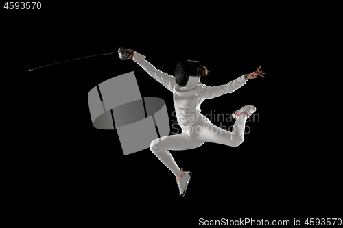 Image of Teen girl in fencing costume with sword in hand isolated on black background