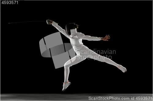 Image of Teen girl in fencing costume with sword in hand isolated on black background