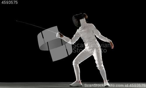 Image of Teen girl in fencing costume with sword in hand isolated on black background