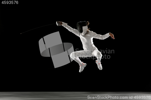 Image of Teen girl in fencing costume with sword in hand isolated on black background