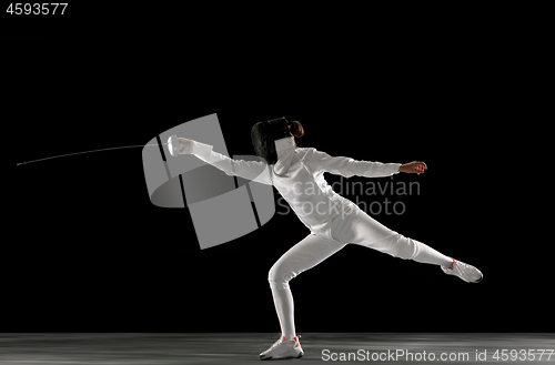 Image of Teen girl in fencing costume with sword in hand isolated on black background