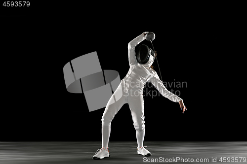 Image of Teen girl in fencing costume with sword in hand isolated on black background