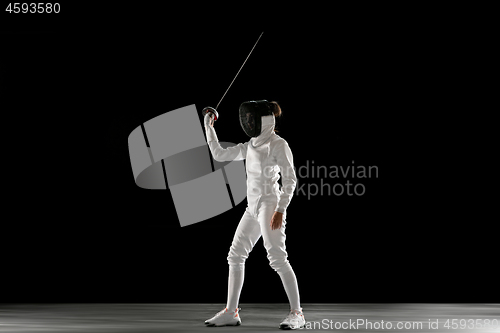 Image of Teen girl in fencing costume with sword in hand isolated on black background