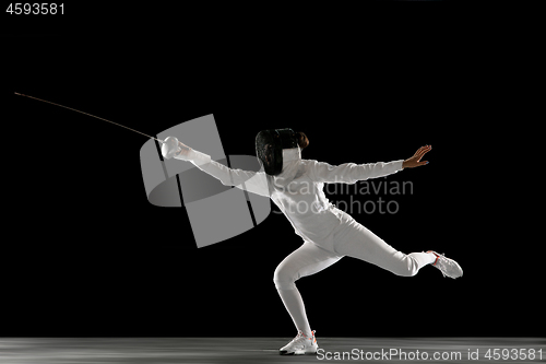 Image of Teen girl in fencing costume with sword in hand isolated on black background