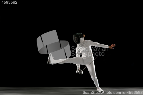 Image of Teen girl in fencing costume with sword in hand isolated on black background