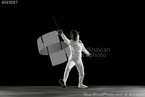 Image of Teen girl in fencing costume with sword in hand isolated on black background