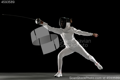 Image of Teen girl in fencing costume with sword in hand isolated on black background