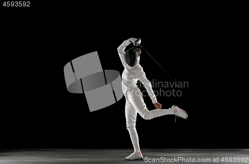 Image of Teen girl in fencing costume with sword in hand isolated on black background