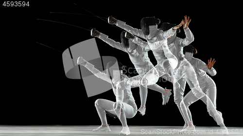 Image of Teen girl in fencing costume with sword in hand isolated on black background