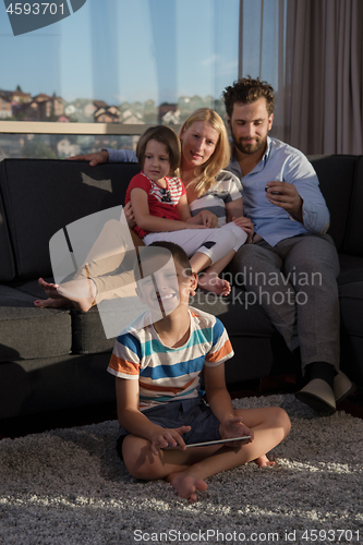 Image of happy young couple spending time with kids at home