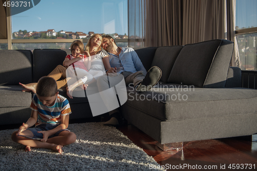 Image of happy young couple spending time with kids at home