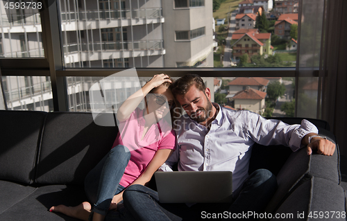 Image of couple relaxing at  home using laptop computers