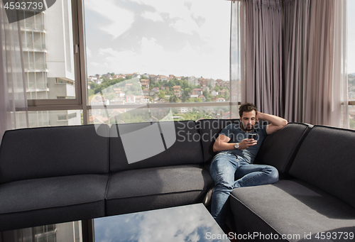 Image of young casual man using a mobile phone at home