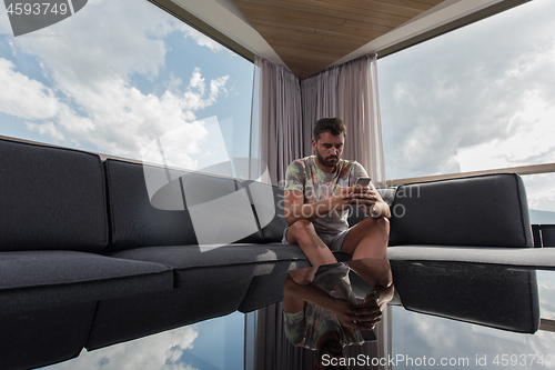 Image of young casual man using a mobile phone at home