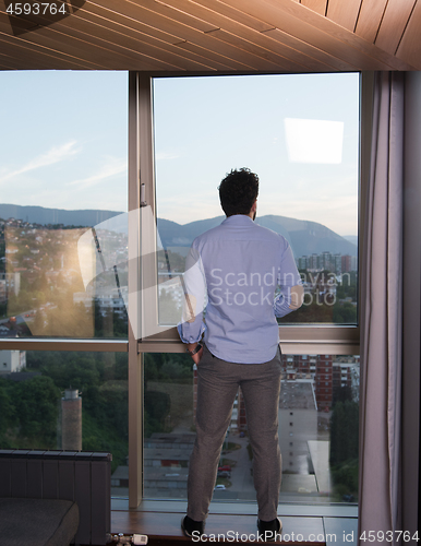 Image of young man enjoying evening coffee by the window