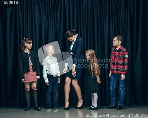 Image of Cute stylish children on dark studio background. The beautiful teen girls and boy standing together