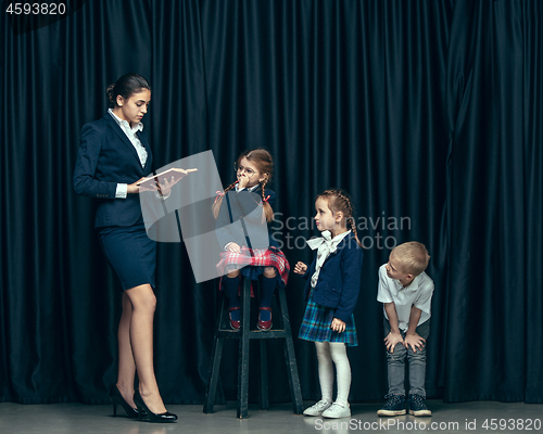 Image of Cute stylish children on dark studio background. The beautiful teen girls and boy standing together