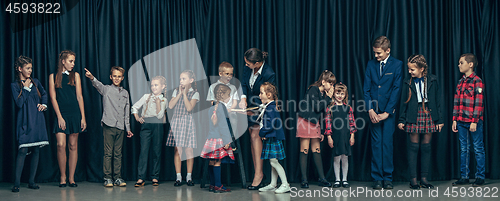 Image of Cute stylish children on dark studio background. The beautiful teen girls and boy standing together