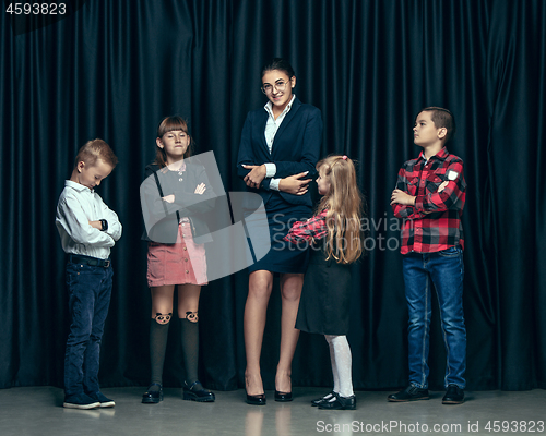 Image of Cute stylish children on dark studio background. The beautiful teen girls and boy standing together