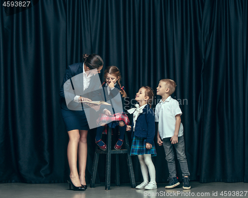 Image of Cute stylish children on dark studio background. The beautiful teen girls and boy standing together