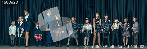 Image of Cute stylish children on dark studio background. The beautiful teen girls and boy standing together