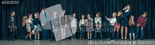 Image of Cute stylish children on dark studio background. The beautiful teen girls and boy standing together