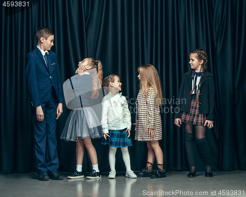 Image of Cute stylish children on dark studio background. The beautiful teen girls and boy standing together