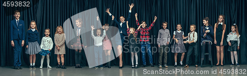 Image of Cute stylish children on dark studio background. The beautiful teen girls and boy standing together