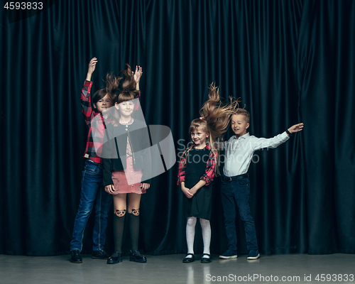 Image of Cute stylish children on dark studio background. The beautiful teen girls and boy standing together