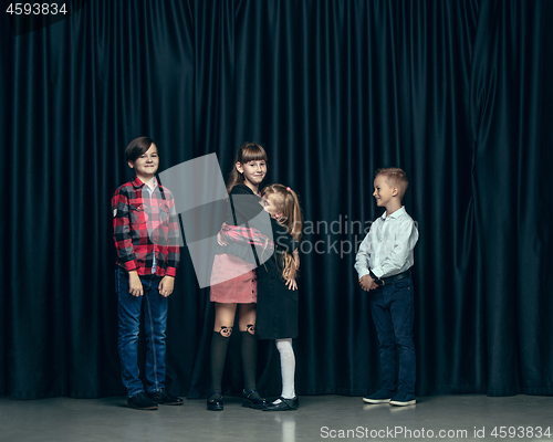 Image of Cute stylish children on dark studio background. The beautiful teen girls and boy standing together