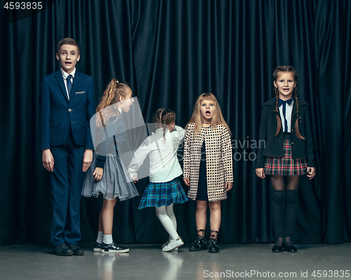 Image of Cute stylish children on dark studio background. The beautiful teen girls and boy standing together