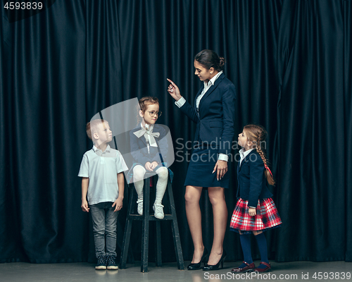Image of Cute stylish children on dark studio background. The beautiful teen girls and boy standing together