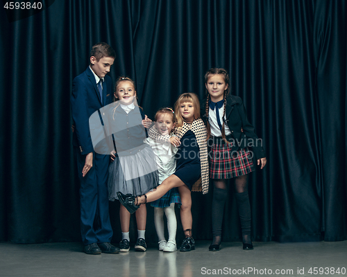 Image of Cute stylish children on dark studio background. The beautiful teen girls and boy standing together