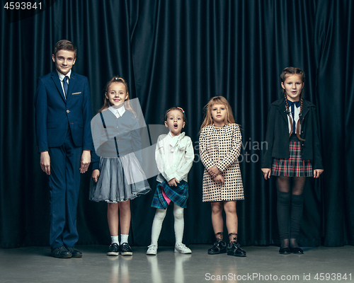 Image of Cute stylish children on dark studio background. The beautiful teen girls and boy standing together