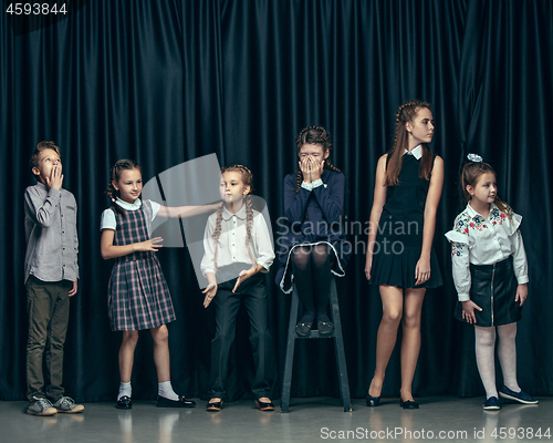 Image of Cute stylish children on dark studio background. The beautiful teen girls and boy standing together