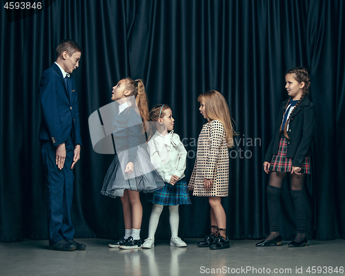 Image of Cute stylish children on dark studio background. The beautiful teen girls and boy standing together