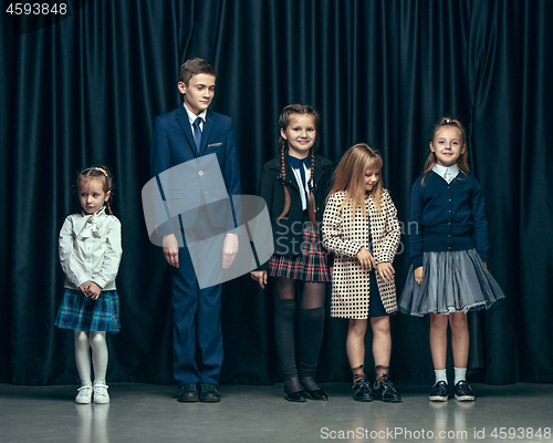 Image of Cute stylish children on dark studio background. The beautiful teen girls and boy standing together