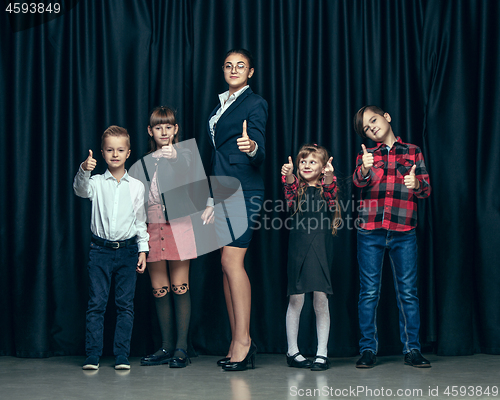 Image of Cute stylish children on dark studio background. The beautiful teen girls and boy standing together