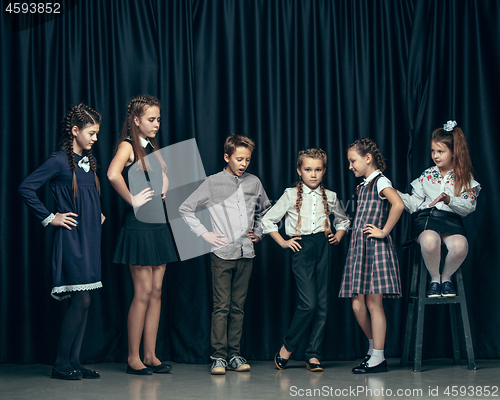 Image of Cute stylish children on dark studio background. The beautiful teen girls and boy standing together