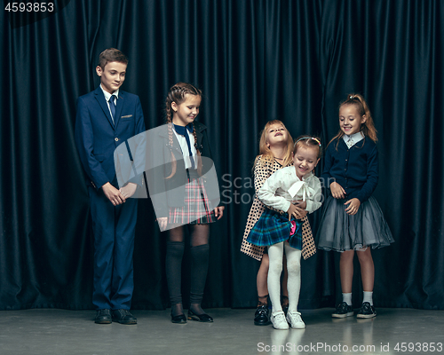 Image of Cute stylish children on dark studio background. The beautiful teen girls and boy standing together