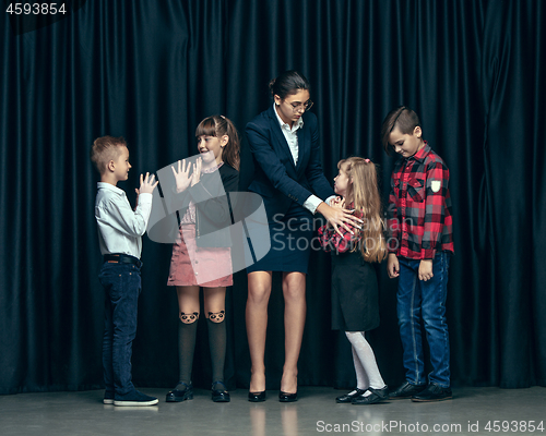 Image of Cute stylish children on dark studio background. The beautiful teen girls and boy standing together