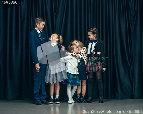 Image of Cute stylish children on dark studio background. The beautiful teen girls and boy standing together