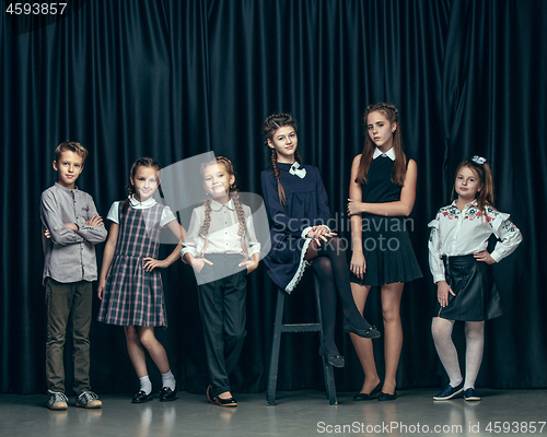 Image of Cute stylish children on dark studio background. The beautiful teen girls and boy standing together