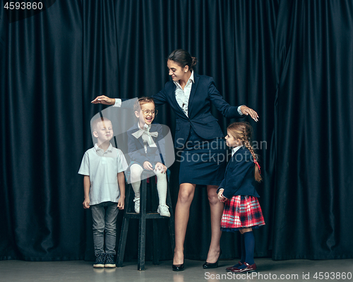 Image of Cute stylish children on dark studio background. The beautiful teen girls and boy standing together