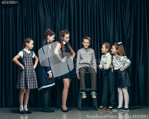 Image of Cute stylish children on dark studio background. The beautiful teen girls and boy standing together