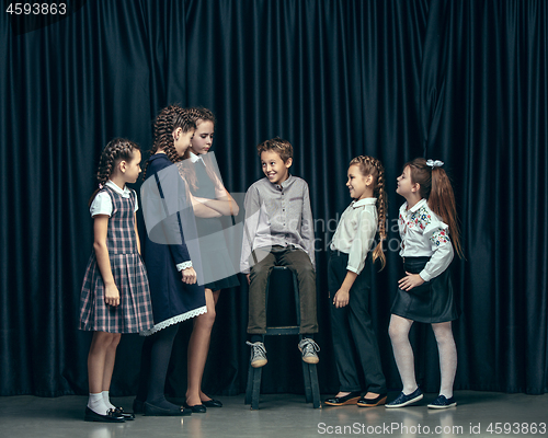 Image of Cute stylish children on dark studio background. The beautiful teen girls and boy standing together